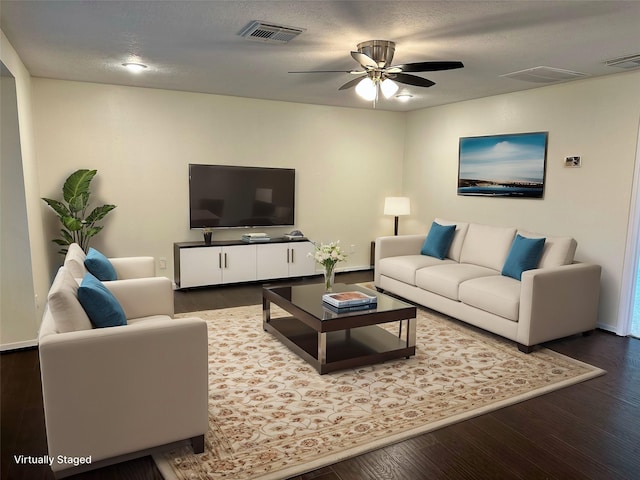 living area with a ceiling fan, visible vents, a textured ceiling, and wood finished floors