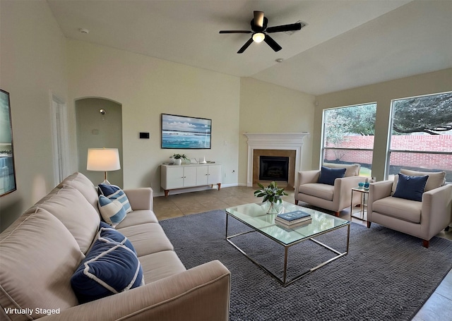 living room with lofted ceiling, ceiling fan, arched walkways, tile patterned flooring, and a fireplace