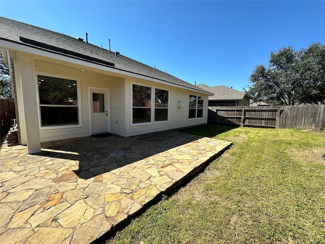 back of house featuring a patio, a lawn, a fenced backyard, and roof with shingles