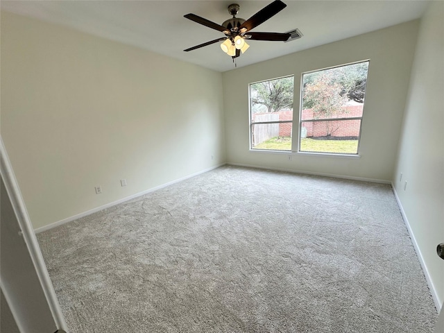 carpeted spare room featuring ceiling fan and baseboards