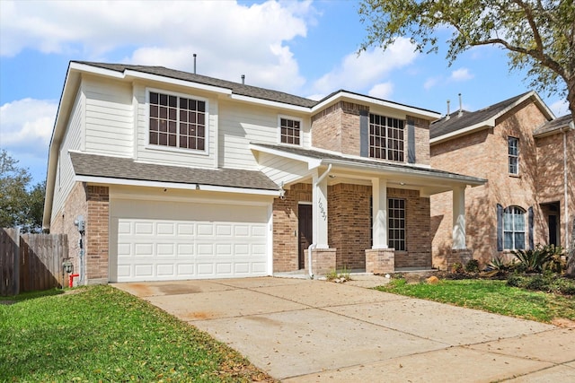 traditional-style home with a front lawn, fence, concrete driveway, an attached garage, and brick siding