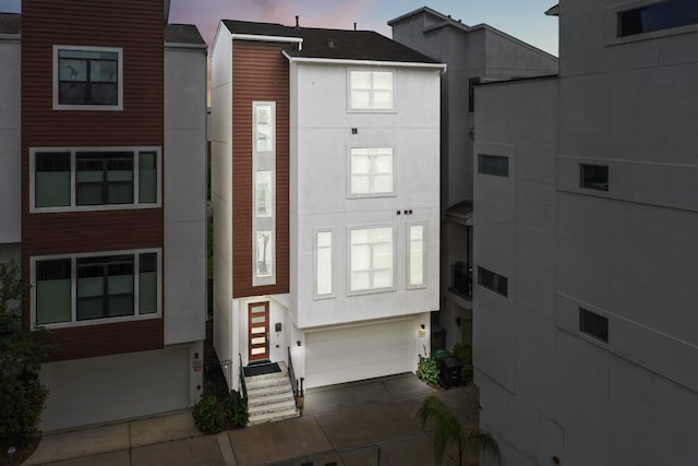 exterior space with entry steps, an attached garage, concrete driveway, and stucco siding