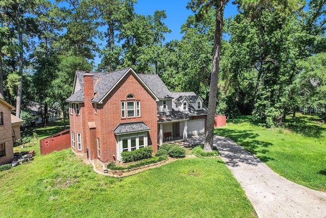 view of front of property with brick siding, a chimney, concrete driveway, a garage, and a front lawn