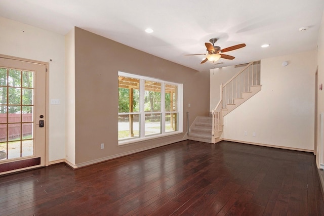 unfurnished living room featuring a healthy amount of sunlight, stairway, and dark wood finished floors