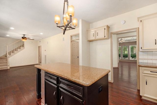 kitchen featuring recessed lighting, ceiling fan with notable chandelier, cream cabinetry, a center island, and dark wood finished floors