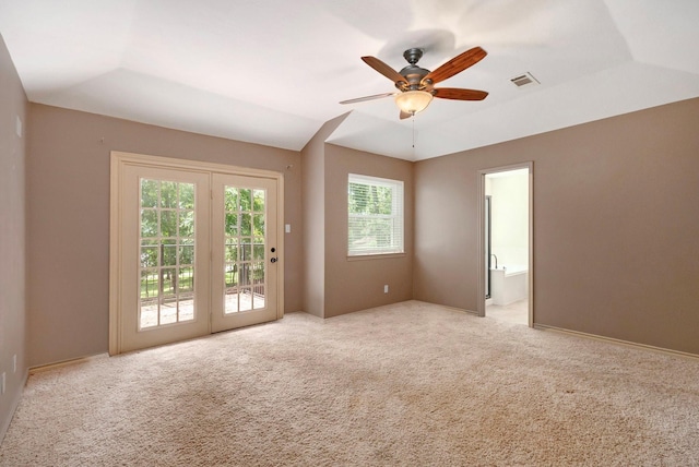 spare room featuring a ceiling fan, lofted ceiling, visible vents, and light carpet