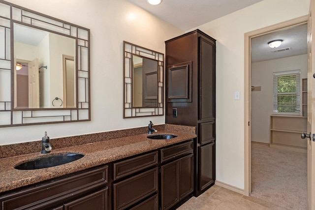 bathroom featuring visible vents, a sink, baseboards, and double vanity