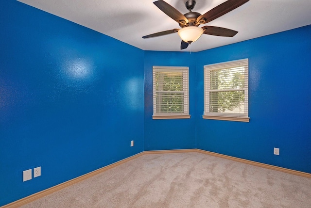 carpeted spare room featuring a ceiling fan and baseboards