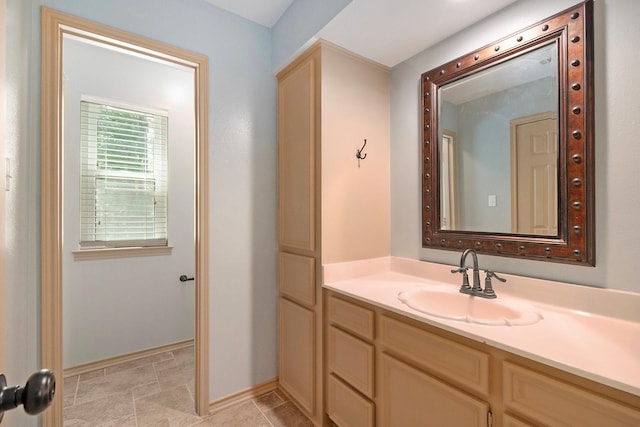 bathroom featuring stone finish floor, vanity, and baseboards