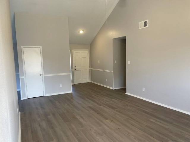 empty room featuring high vaulted ceiling, dark wood finished floors, visible vents, and baseboards