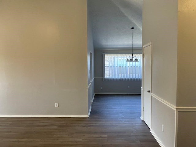 interior space with baseboards, a chandelier, and dark wood finished floors