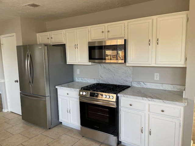 kitchen with visible vents, light stone countertops, stainless steel appliances, a textured ceiling, and white cabinetry