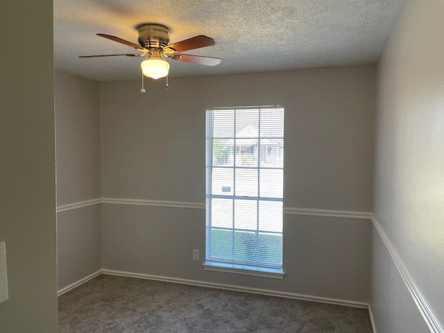 empty room with a textured ceiling, carpet floors, ceiling fan, and plenty of natural light