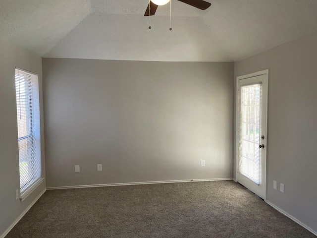 carpeted spare room featuring a ceiling fan, vaulted ceiling, a textured ceiling, and baseboards