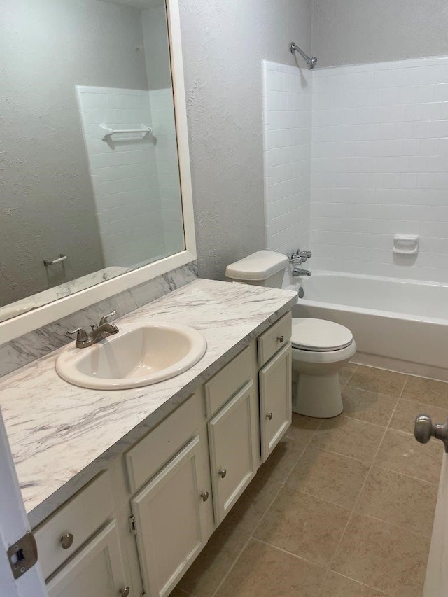 full bath featuring a textured wall, tile patterned flooring, toilet, vanity, and shower / washtub combination