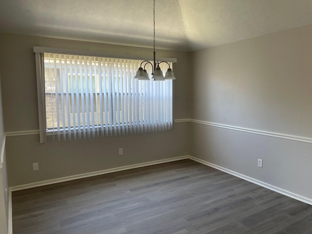 spare room featuring a notable chandelier, a textured ceiling, baseboards, and dark wood-type flooring