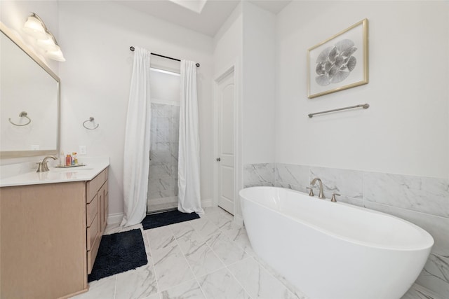 full bath featuring a freestanding bath, marble finish floor, vanity, and tile walls