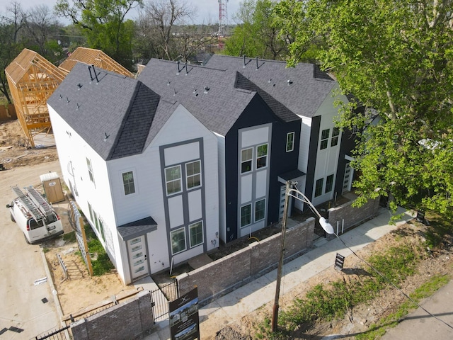 view of front of home with roof with shingles and fence