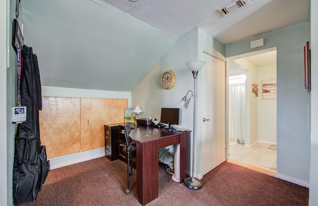 office featuring lofted ceiling, dark colored carpet, visible vents, and baseboards