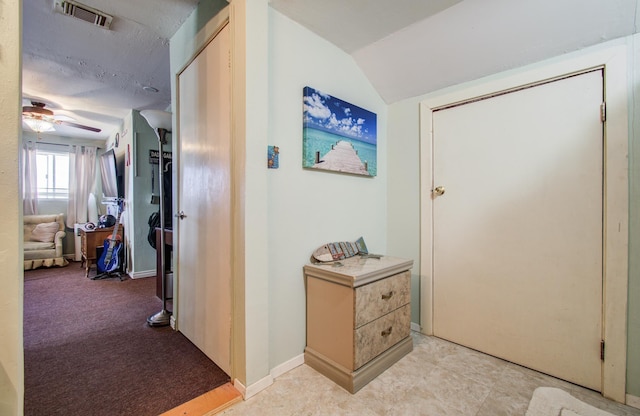 hall featuring lofted ceiling, visible vents, and baseboards