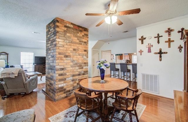 dining space featuring visible vents, a textured ceiling, and wood finished floors