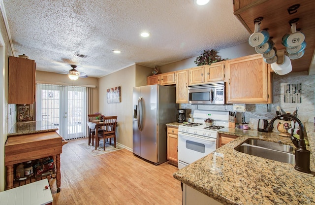 kitchen featuring stainless steel appliances, visible vents, a ceiling fan, a sink, and light wood-type flooring