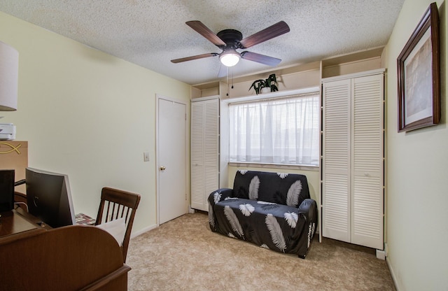 carpeted office featuring baseboards, a ceiling fan, and a textured ceiling