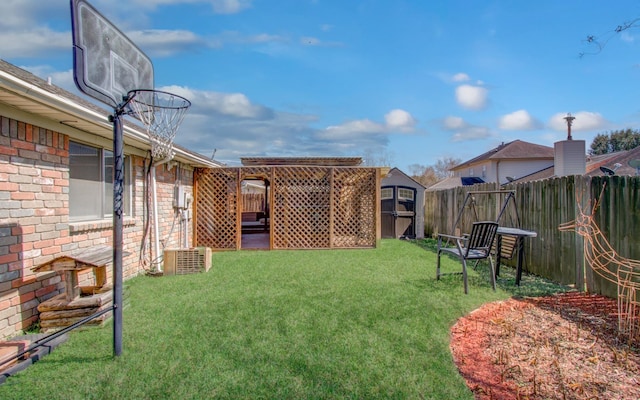 view of yard with an outbuilding, central AC, fence, and a storage unit