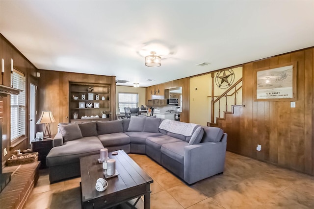 living room featuring stairway, visible vents, and wooden walls