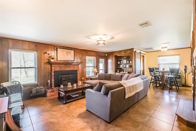 living room with a healthy amount of sunlight, light tile patterned floors, built in shelves, and visible vents