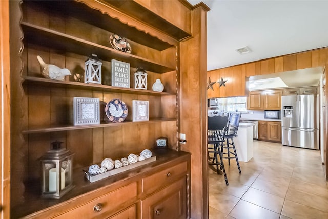 interior space with brown cabinets, open shelves, dark countertops, visible vents, and appliances with stainless steel finishes