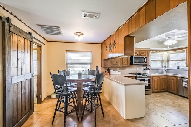 kitchen with a peninsula, a barn door, visible vents, and appliances with stainless steel finishes