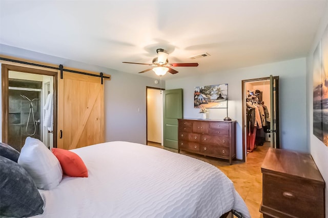 bedroom featuring a barn door, visible vents, ceiling fan, a walk in closet, and a closet