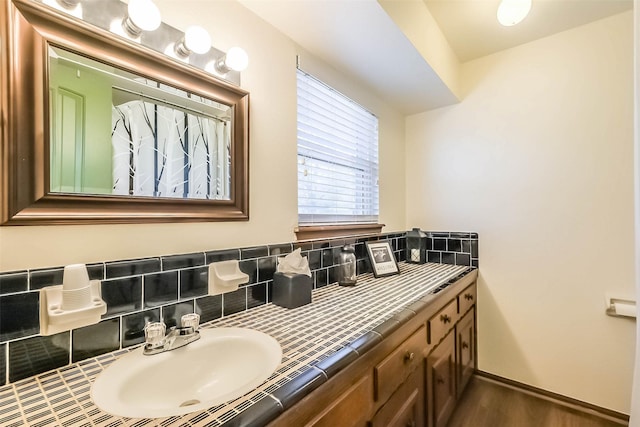 bathroom with backsplash, wood finished floors, vanity, and baseboards