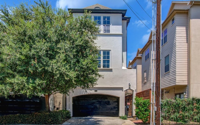 view of front of property with a garage, driveway, fence, and stucco siding