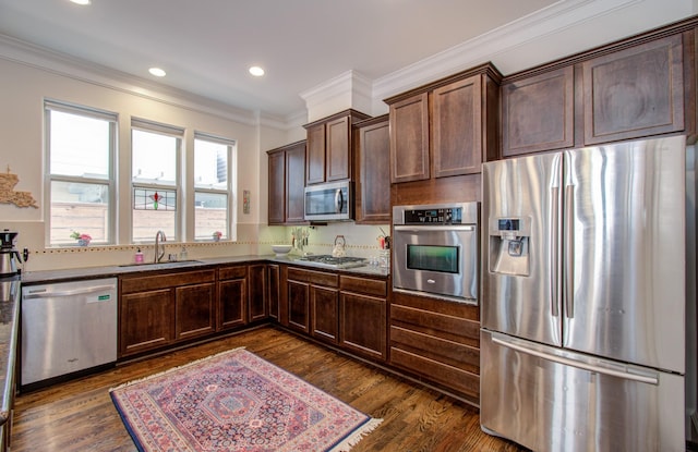 kitchen featuring recessed lighting, stainless steel appliances, a sink, ornamental molding, and dark wood finished floors