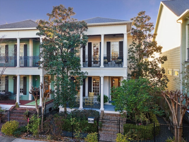 view of front of property with a porch, a fenced front yard, and a balcony