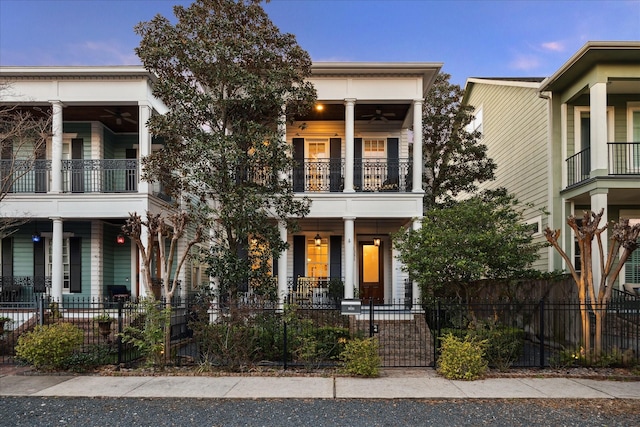 view of front facade with a balcony, a fenced front yard, a porch, and a ceiling fan