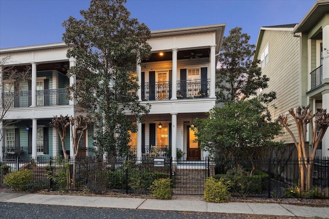 view of front facade featuring a balcony, a fenced front yard, a gate, and a porch