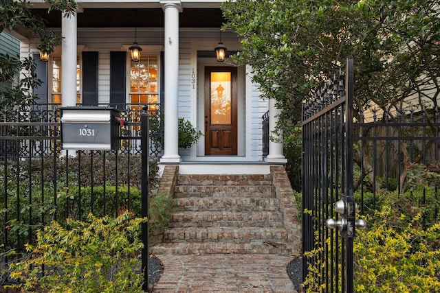 view of exterior entry featuring covered porch, fence, and a gate