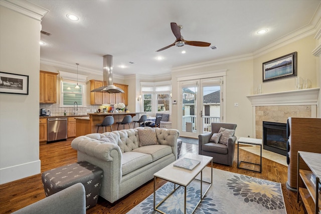 living area featuring crown molding, visible vents, dark wood finished floors, and a tiled fireplace