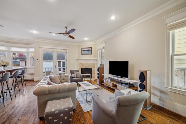 living room featuring ornamental molding, a tile fireplace, plenty of natural light, and wood finished floors