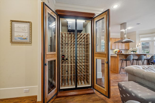 wine room featuring crown molding and wood finished floors