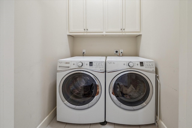 laundry area featuring light tile patterned floors, independent washer and dryer, cabinet space, and baseboards