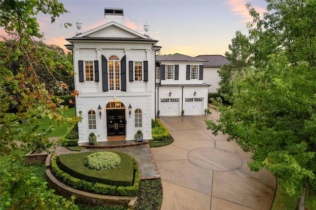 greek revival inspired property featuring concrete driveway and an attached garage