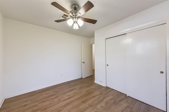 unfurnished bedroom with ceiling fan, light wood-style flooring, visible vents, baseboards, and a closet