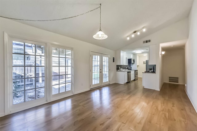 unfurnished living room featuring lofted ceiling, french doors, wood finished floors, and visible vents