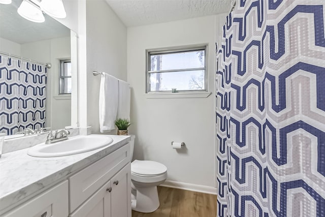 full bathroom with a textured ceiling, toilet, wood finished floors, vanity, and baseboards