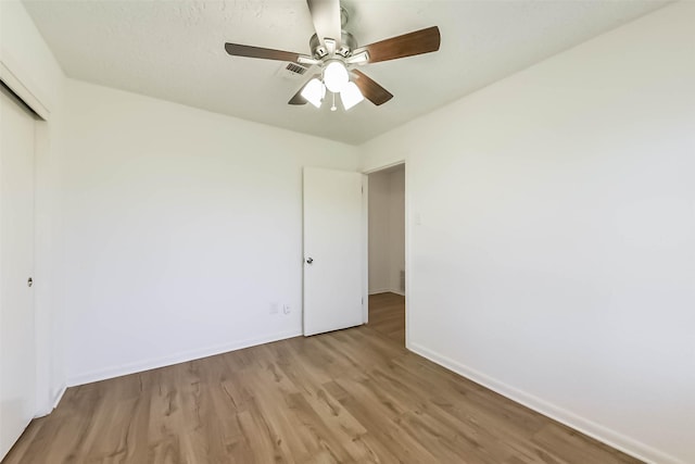 unfurnished bedroom with ceiling fan, a closet, wood finished floors, and baseboards