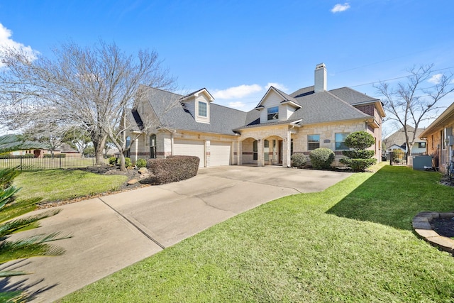 view of front facade featuring driveway, a garage, stone siding, fence, and a front lawn